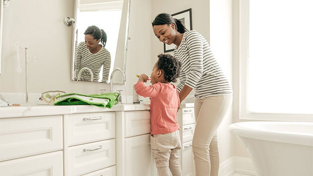 Mother and child brushing teeth in bathroom
